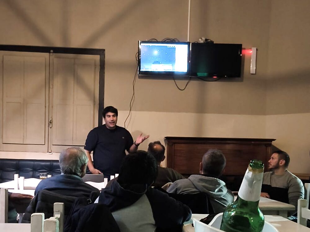 Bernardo da una charla en un bar, con una imagen del cielo en la pantalla