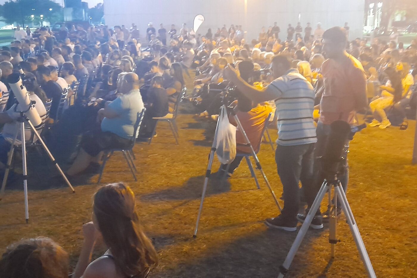 Multitud reunida de noche alrededor de varios telescopios